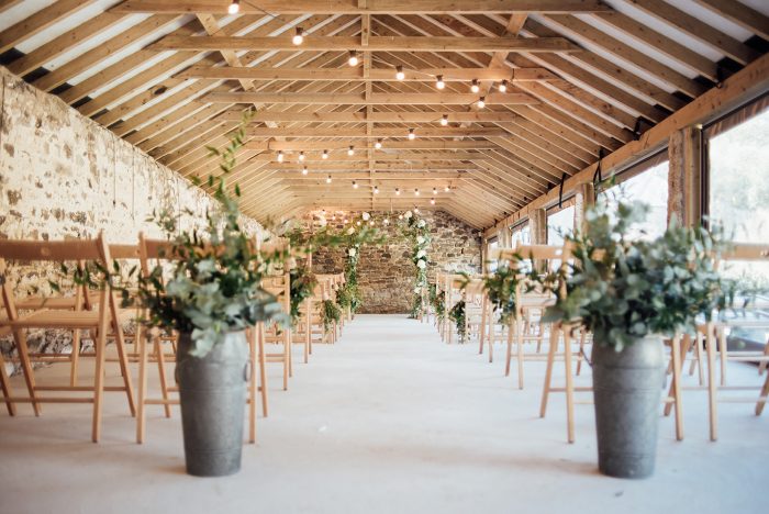 The-inside-of-the-Cowyard-Barn-rustic-party-and-reception-space-set-for-a-wedding-ceremony-at-Pengenna-Manor-Cornwall-wedding-venue-1-700x468