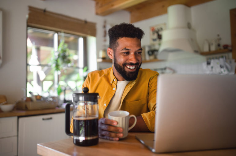 Man smiling at laptop holiday a mug