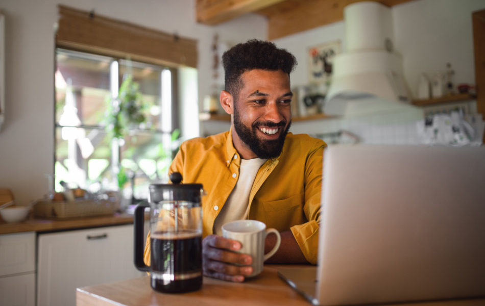 Man smiling at laptop holiday a mug