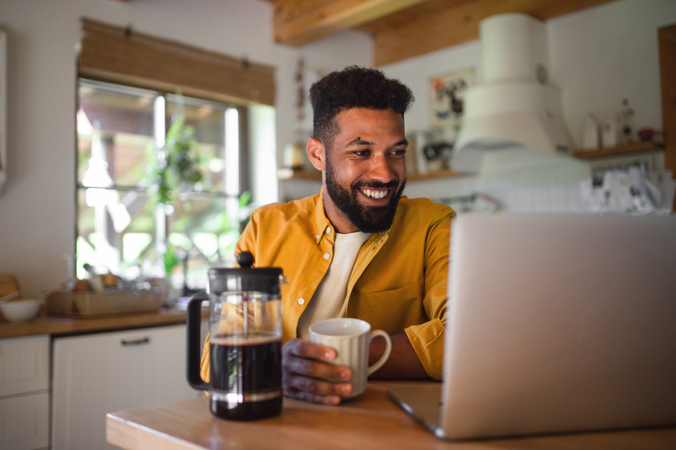 Man smiling at laptop holiday a mug