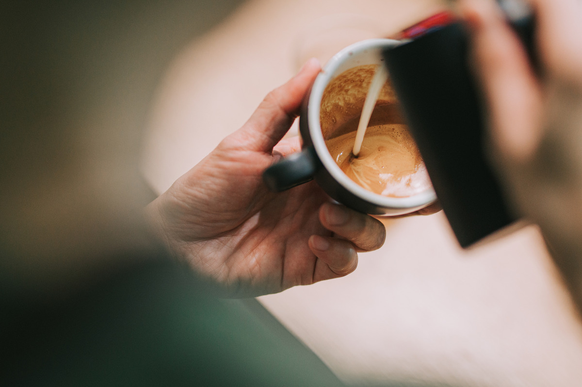 Coffee creamer being poured into a cup of coffee